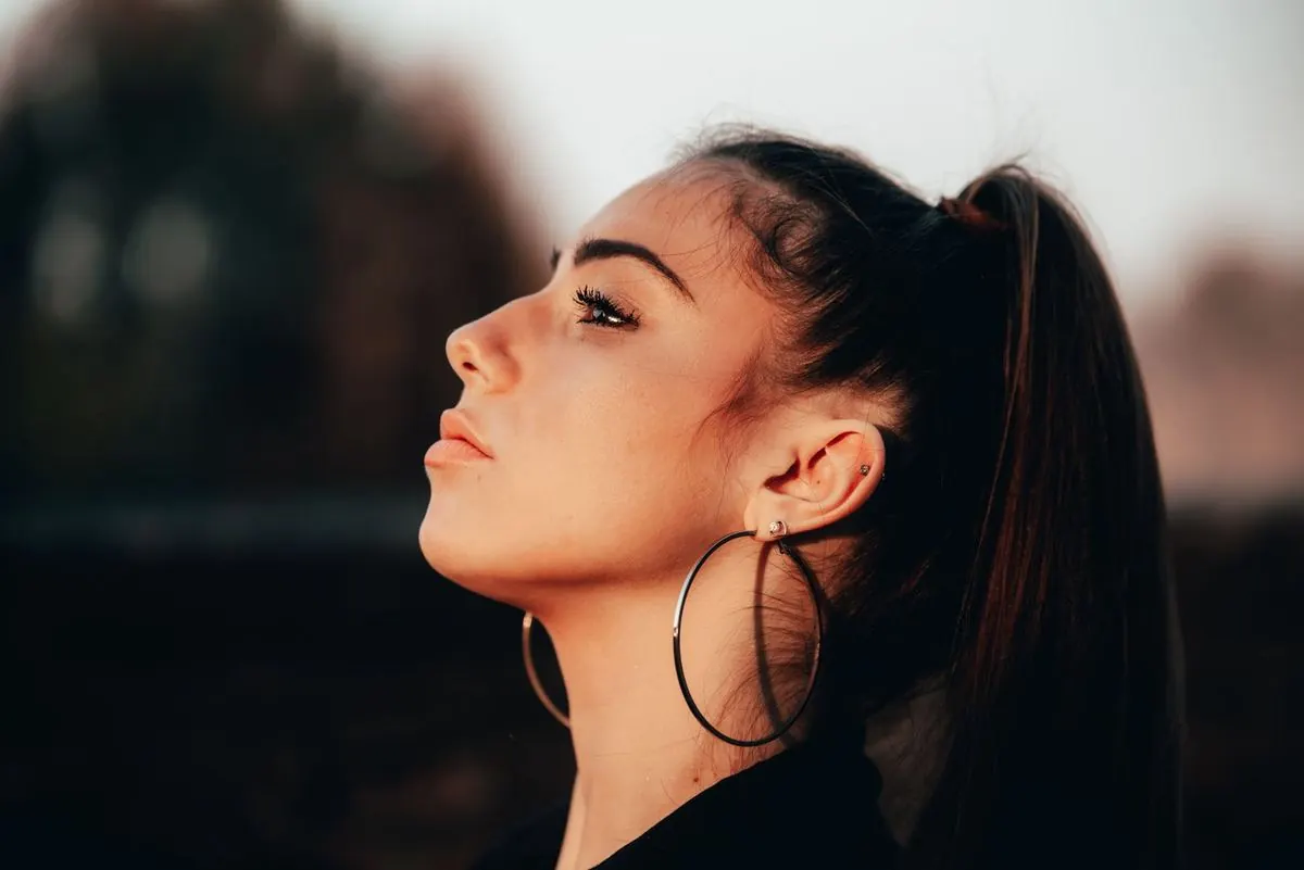 Side profile of a woman with hoop earrings showing the chin and jaw