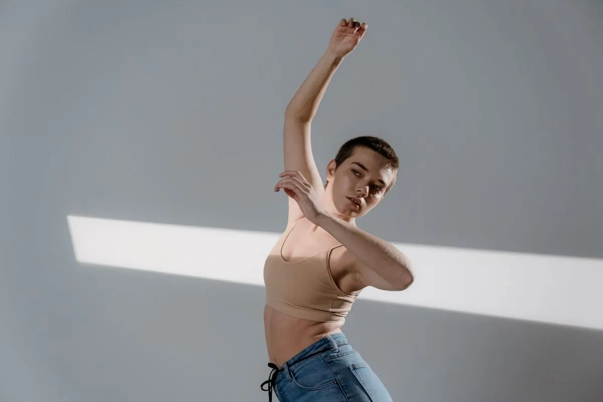 Woman in a beige top raising her arm in soft studio light