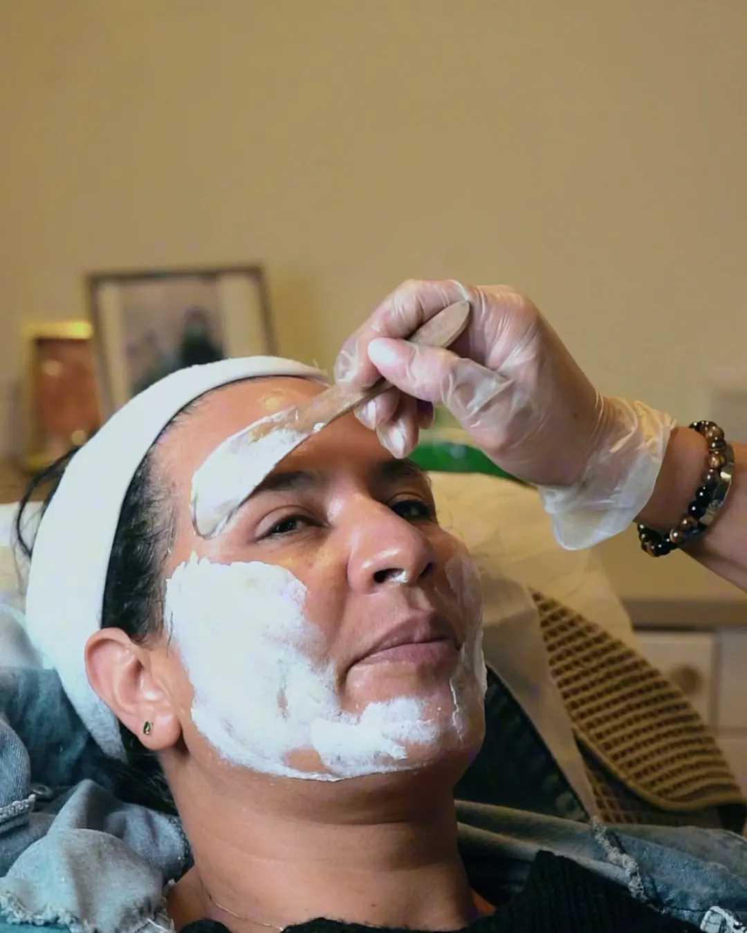 Client having a cream mask applied during a facial
