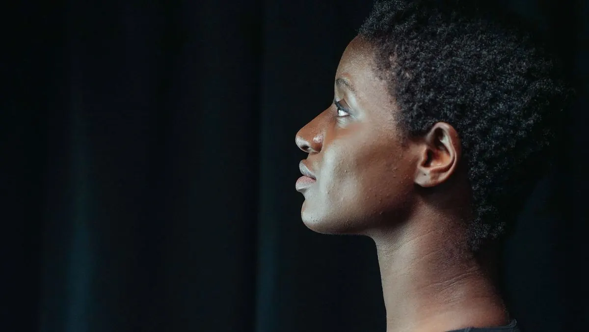 Side profile of a woman showing a defined jawline against a dark background