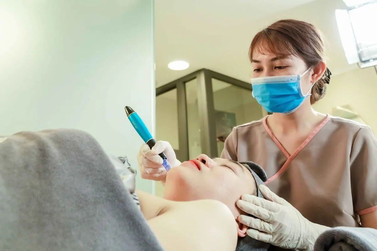 Practitioner using a microneedling pen on a client's cheek