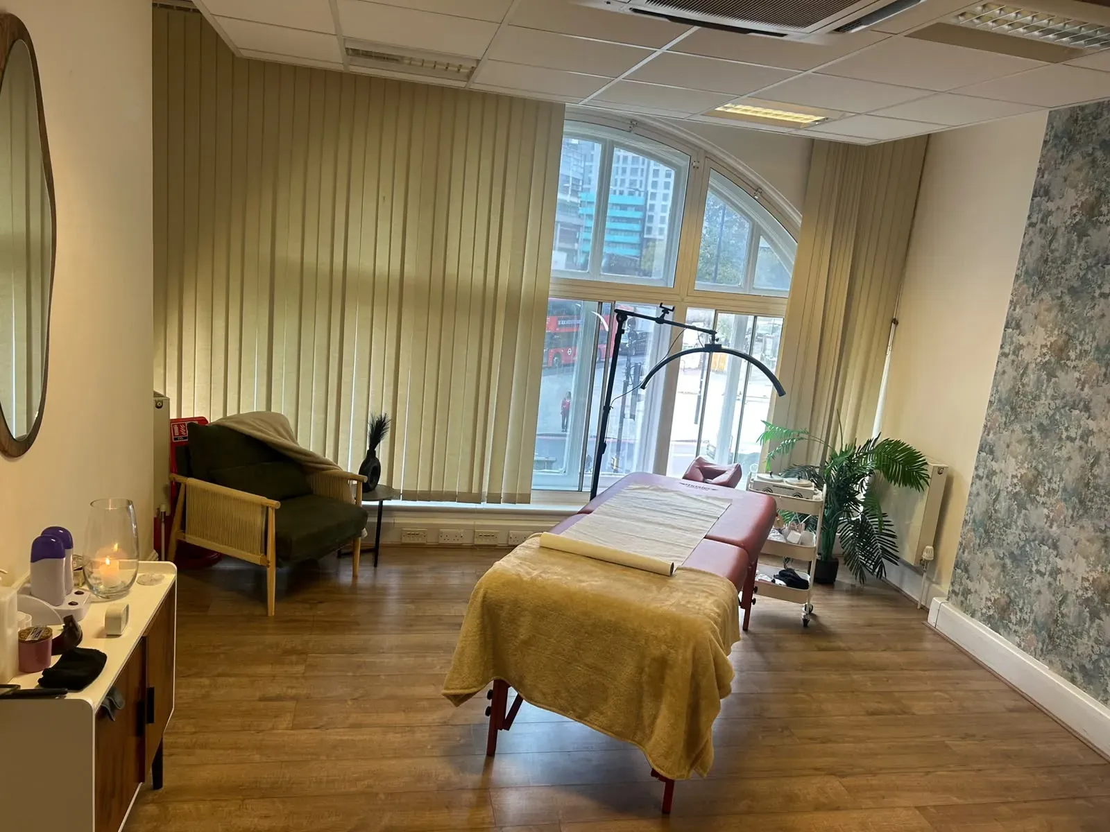 Private treatment room with a couch, tall arched windows and floral wallpaper