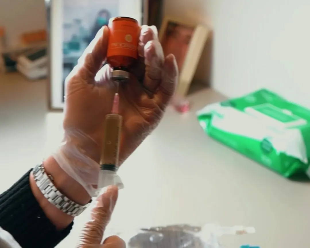 Gloved practitioner drawing up an injection from a vial